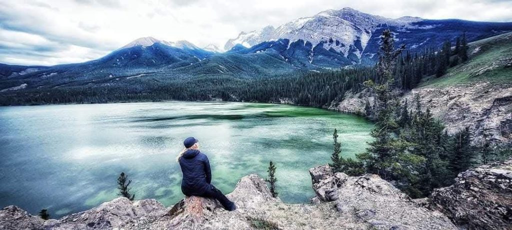 Solohiker Rayu is sitting on a rock in a Canadian landscape